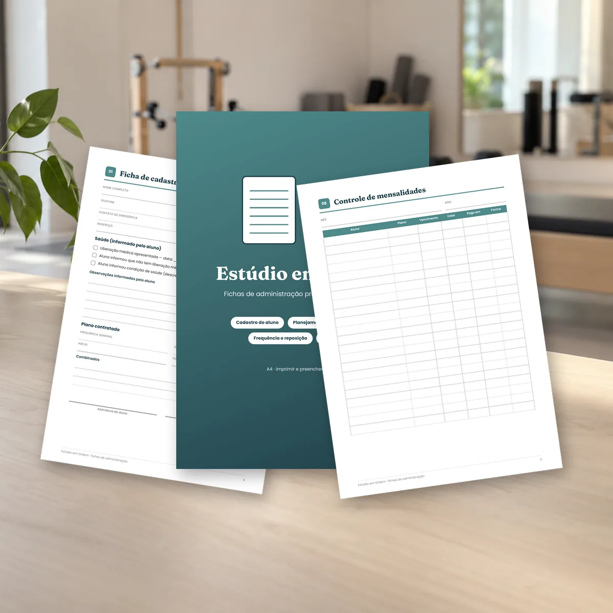 Fichas do Estúdio em Ordem sobre a mesa de um estúdio de pilates. Montagem com páginas reais do PDF.